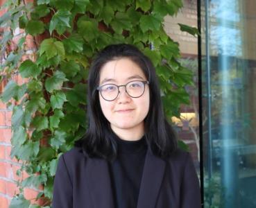 Head shot of Jocelyn Lee in front of a wall with green ivy hanging off it